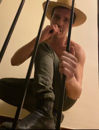 Portrait de Ben Arrigoni avec un chapeau, derrière une rampe