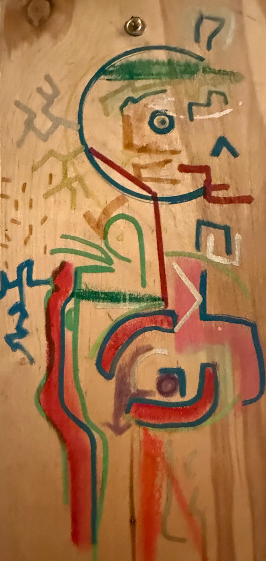 Figure tracée en lignes de couleur sur une planche de bois clair