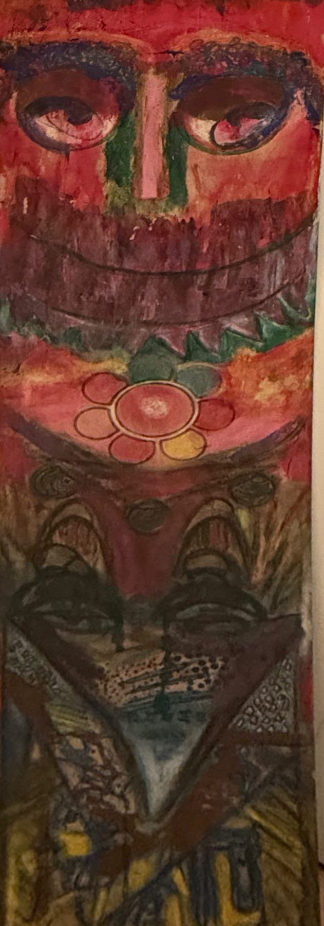 Panneau vertical : un grand visage rouge aux yeux ronds, une fleur, des motifs en dessous